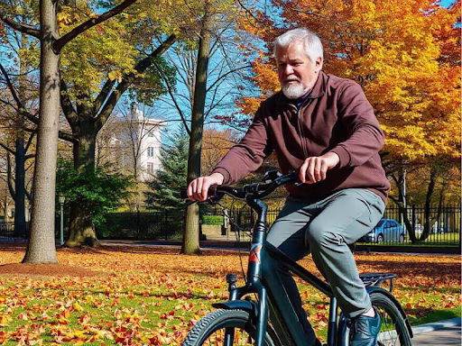 A senior man enjoys a ride on his electric bike, surrounded by vibrant fall foliage and a clear blue sky.